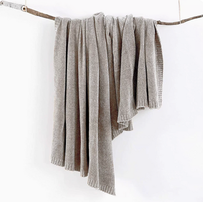 Gray vertical rib chenille knit solid throw blanket hanging over a wooden branch