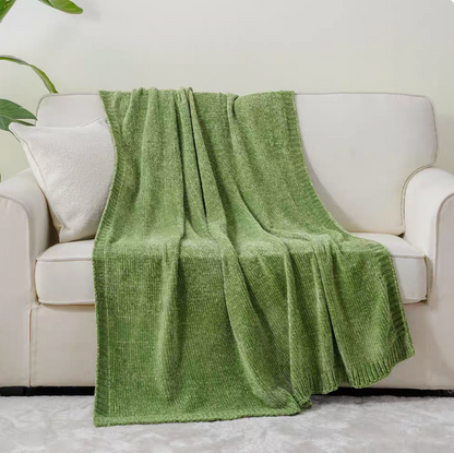 Green vertical rib chenille knit solid throw blanket draped over a white sofa