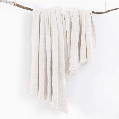 Ivory vertical rib chenille knit solid throw blanket hanging over a wooden branch