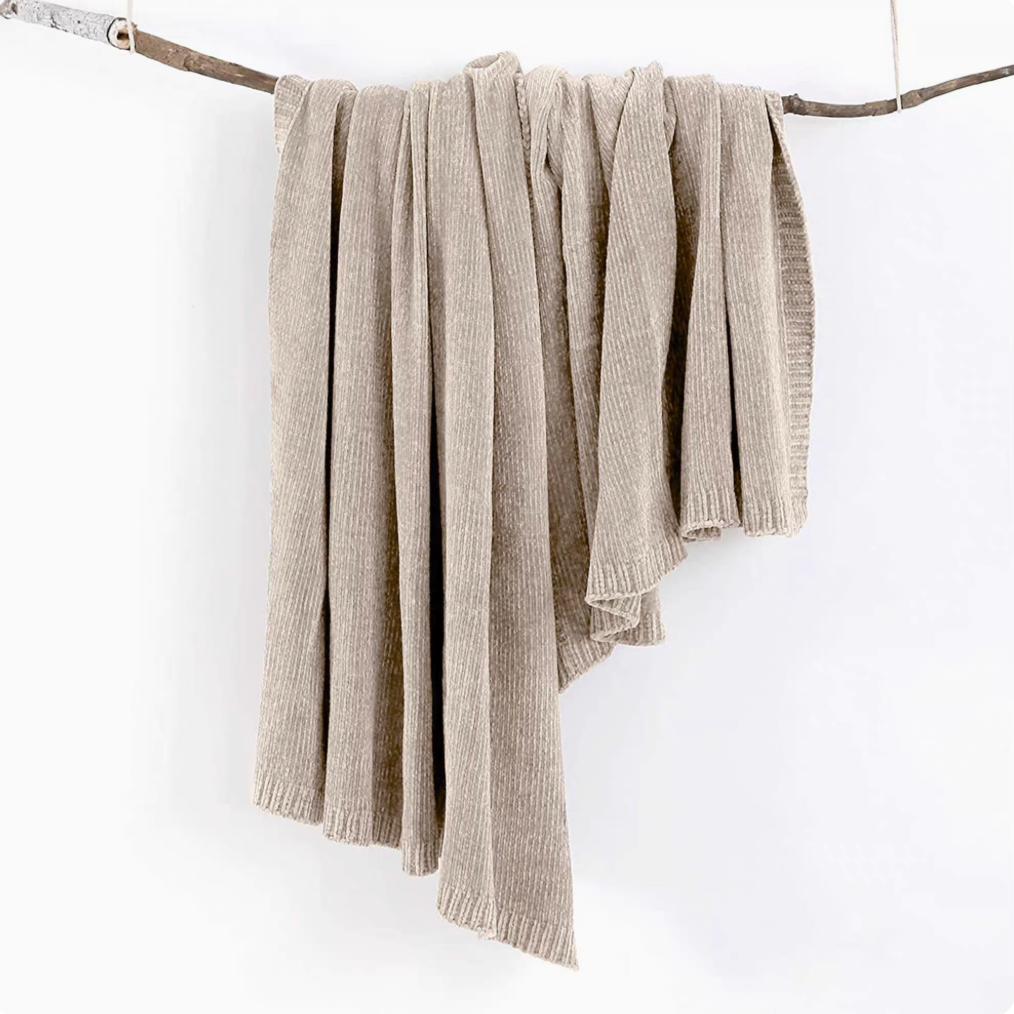 Khaki vertical rib chenille knit solid throw blanket hanging over a wooden branch