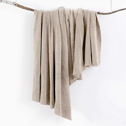 Khaki vertical rib chenille knit solid throw blanket hanging over a wooden branch