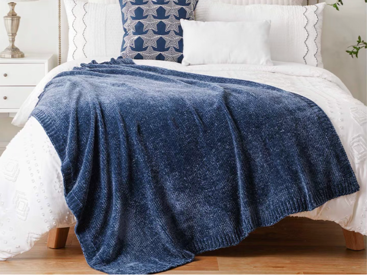 Navy blue vertical rib chenille knit solid throw blanket draped across a white bed