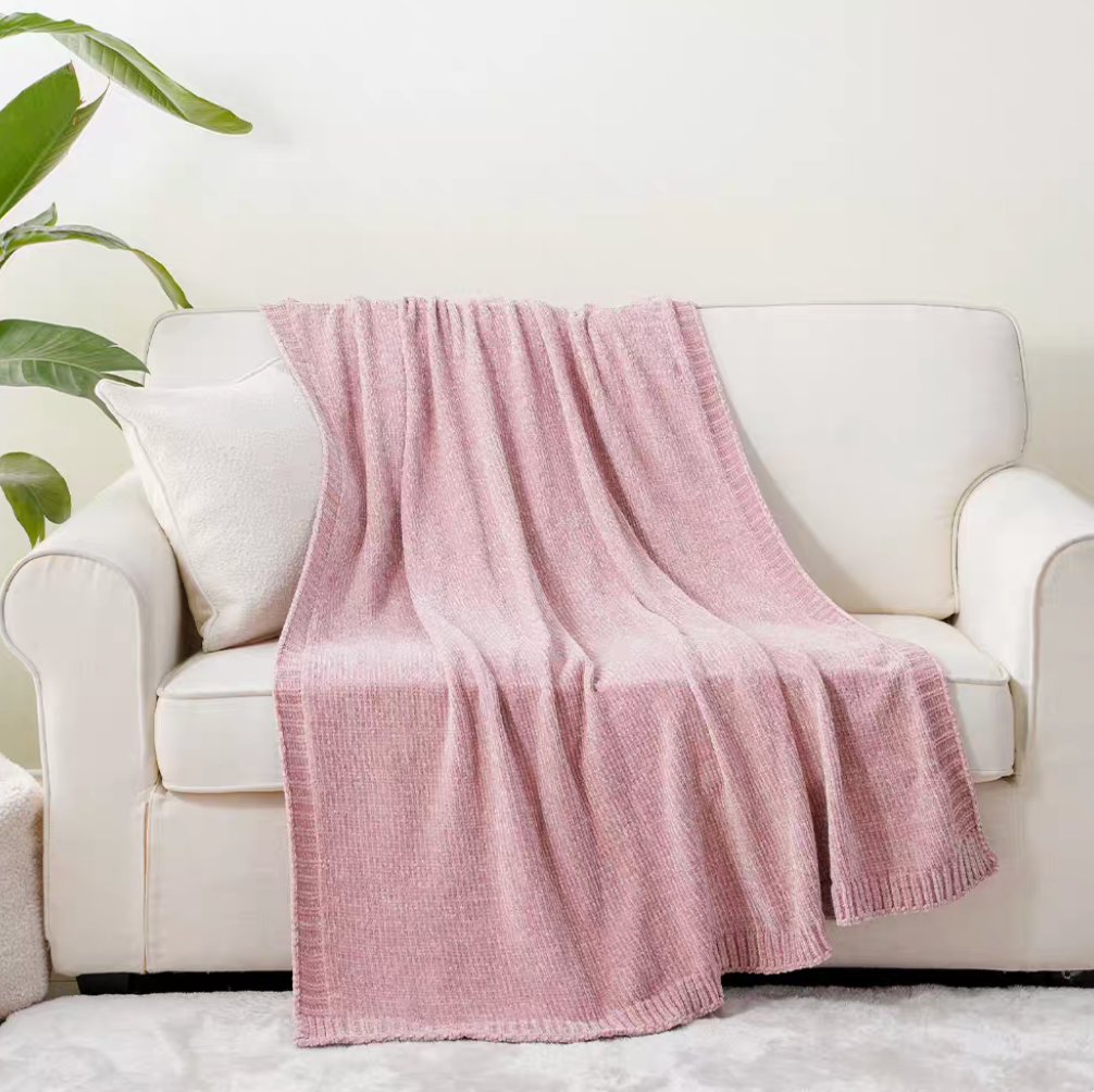 Pink vertical rib chenille knit solid throw blanket draped over a white sofa