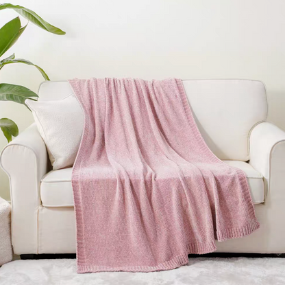 Pink vertical rib chenille knit solid throw blanket draped over a white sofa