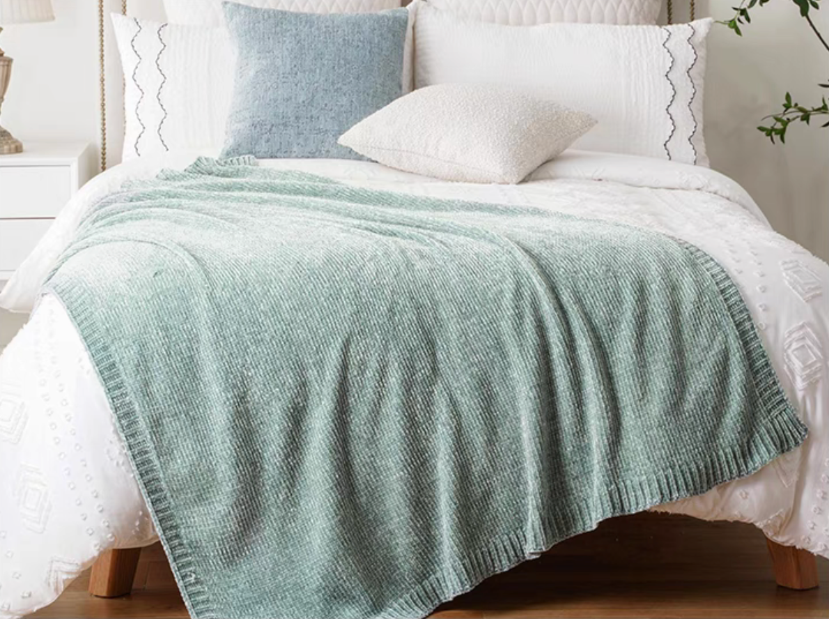 Teal vertical rib chenille knit solid throw blanket layered across a white bed