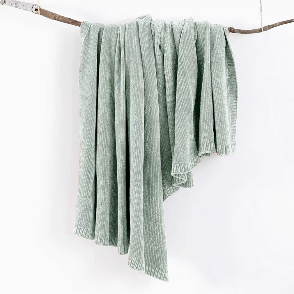 Teal vertical rib chenille knit solid throw blanket hanging over a wooden branch