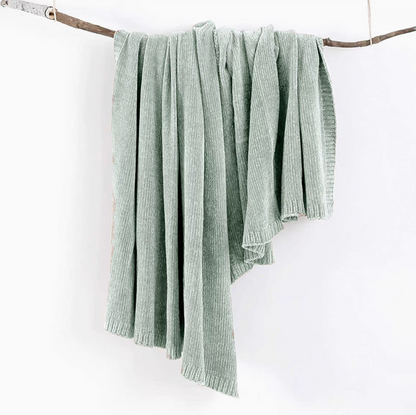 Teal vertical rib chenille knit solid throw blanket hanging over a wooden branch