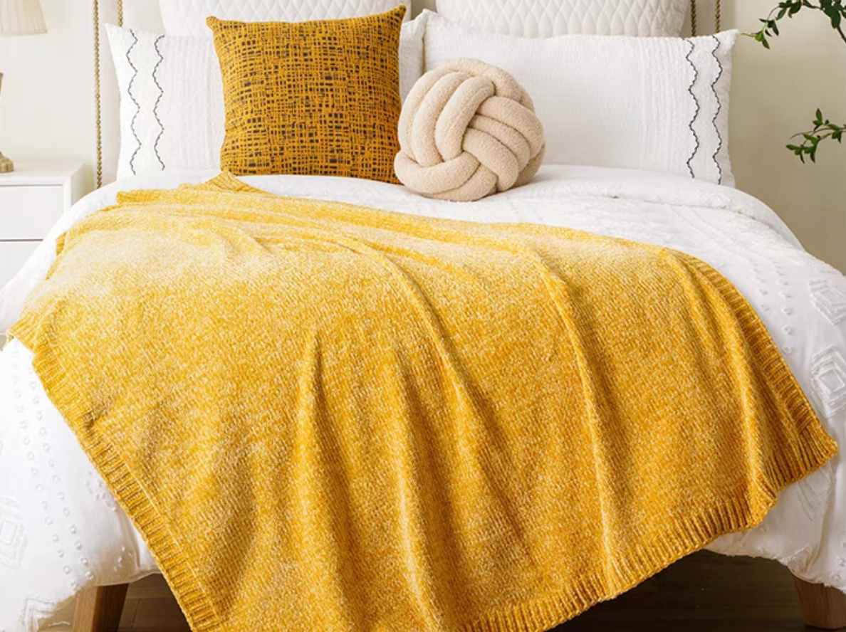 Yellow vertical rib chenille knit solid throw blanket spread across a white bed