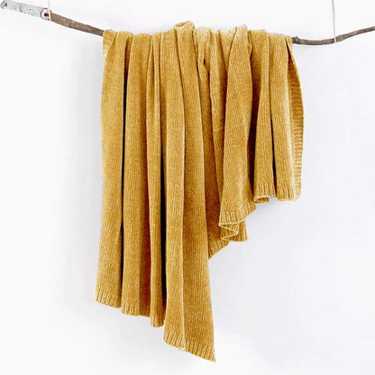 Yellow vertical rib chenille knit solid throw blanket hanging over a wooden branch