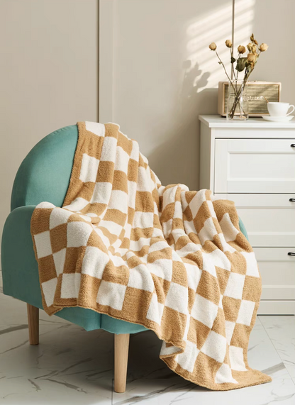 Light khaki checkered blanket draped across teal armchair showing natural folds and plush cozy surface