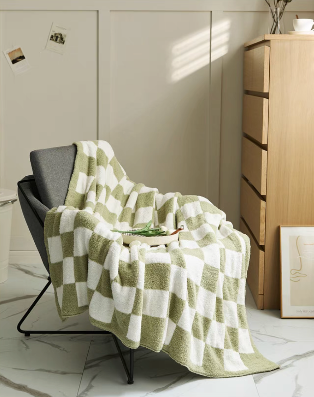 Matcha green checkered blanket draped over lounge chair in sunlit room showing soft folds and relaxed styling