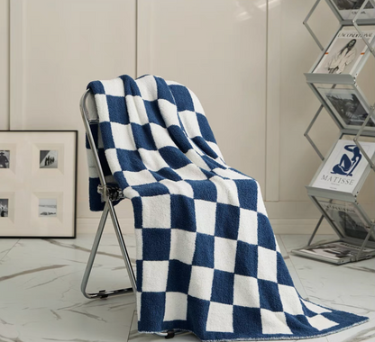 Navy blue checkered blanket cascading over metal chair showing full length drape and soft plush texture