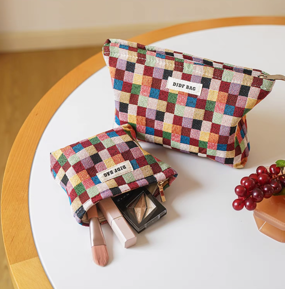 Vibrant Checkered Travel Makeup Bag in multi-colored checkered pattern showing both small and large pouches on round table with makeup items