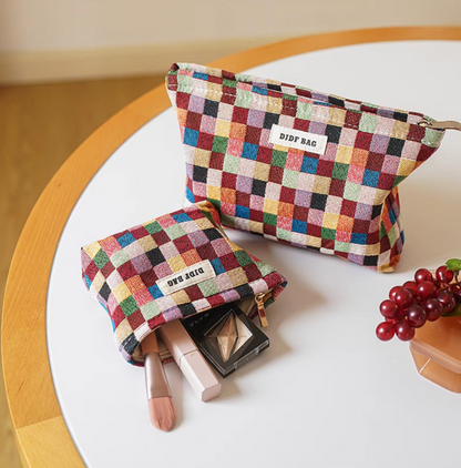 Vibrant Checkered Travel Makeup Bag in multi-colored checkered pattern showing both small and large pouches on round table with makeup items