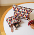 Vibrant Checkered Travel Makeup Bag in multi-colored checkered pattern showing both small and large pouches on round table with makeup items