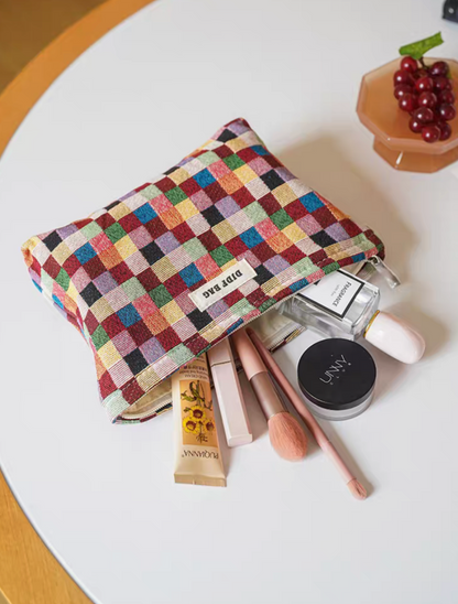 Small size Vibrant Checkered Travel Makeup Bag in multi-colored checkered pattern opened with cosmetics including brush, powder, and skincare items