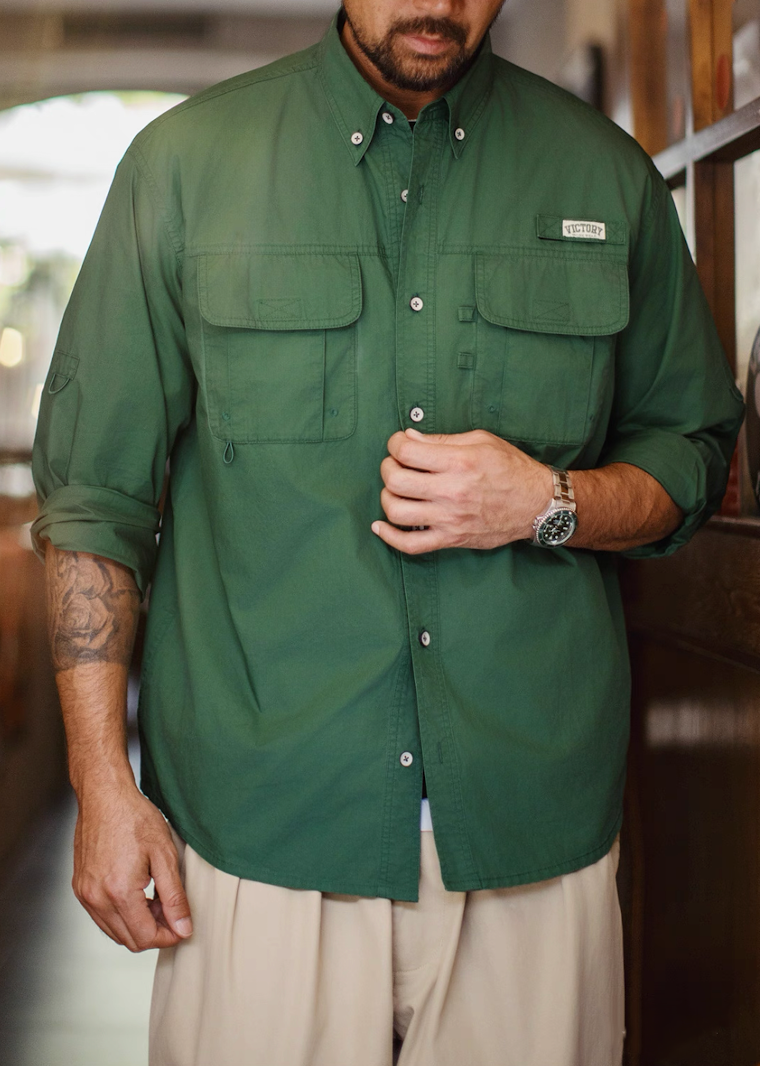 Man wearing hunter green workwear shirt with rolled sleeves and beige pants