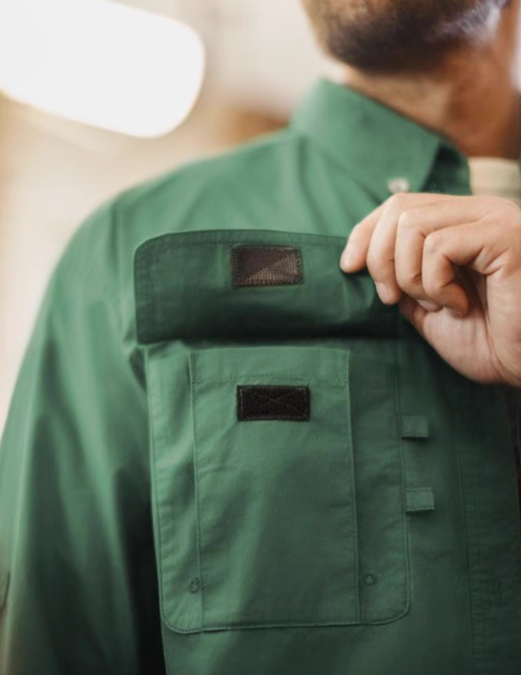 Close-up of model lifting velcro flap chest pocket on green utility shirt