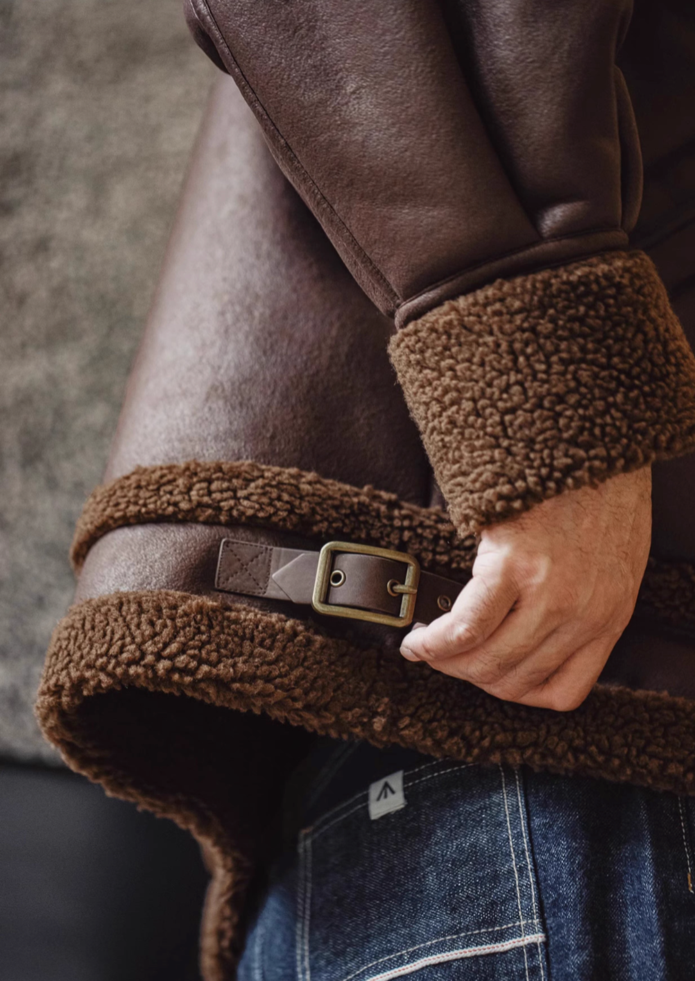Detail view of Vintage-Inspired Faux Sherpa B3 Bomber Jacket in Coffee Brown showing sherpa hem lining and adjustable buckle strap
