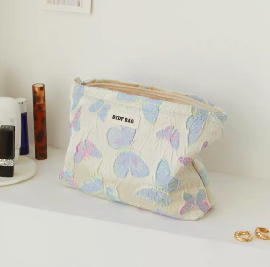 Vintage Butterfly Pattern Portable Makeup Bag in laser butterfly design large pouch placed on counter with zipper open and accessories nearby

