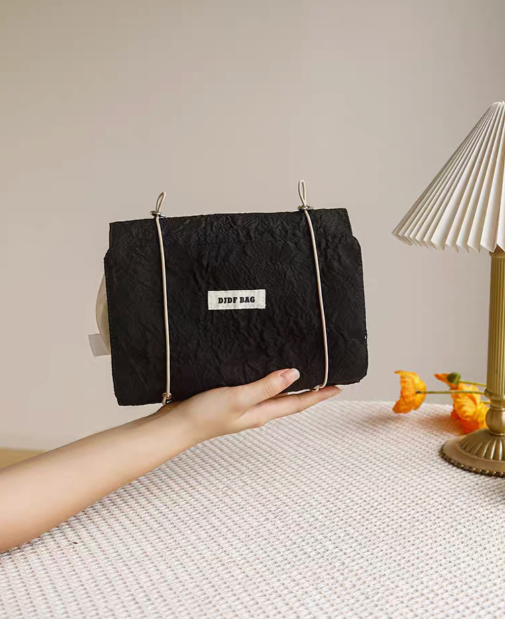 Vintage Chic Waterproof Travel Makeup Bag in black color held in hand showing compact portable design on textured surface
