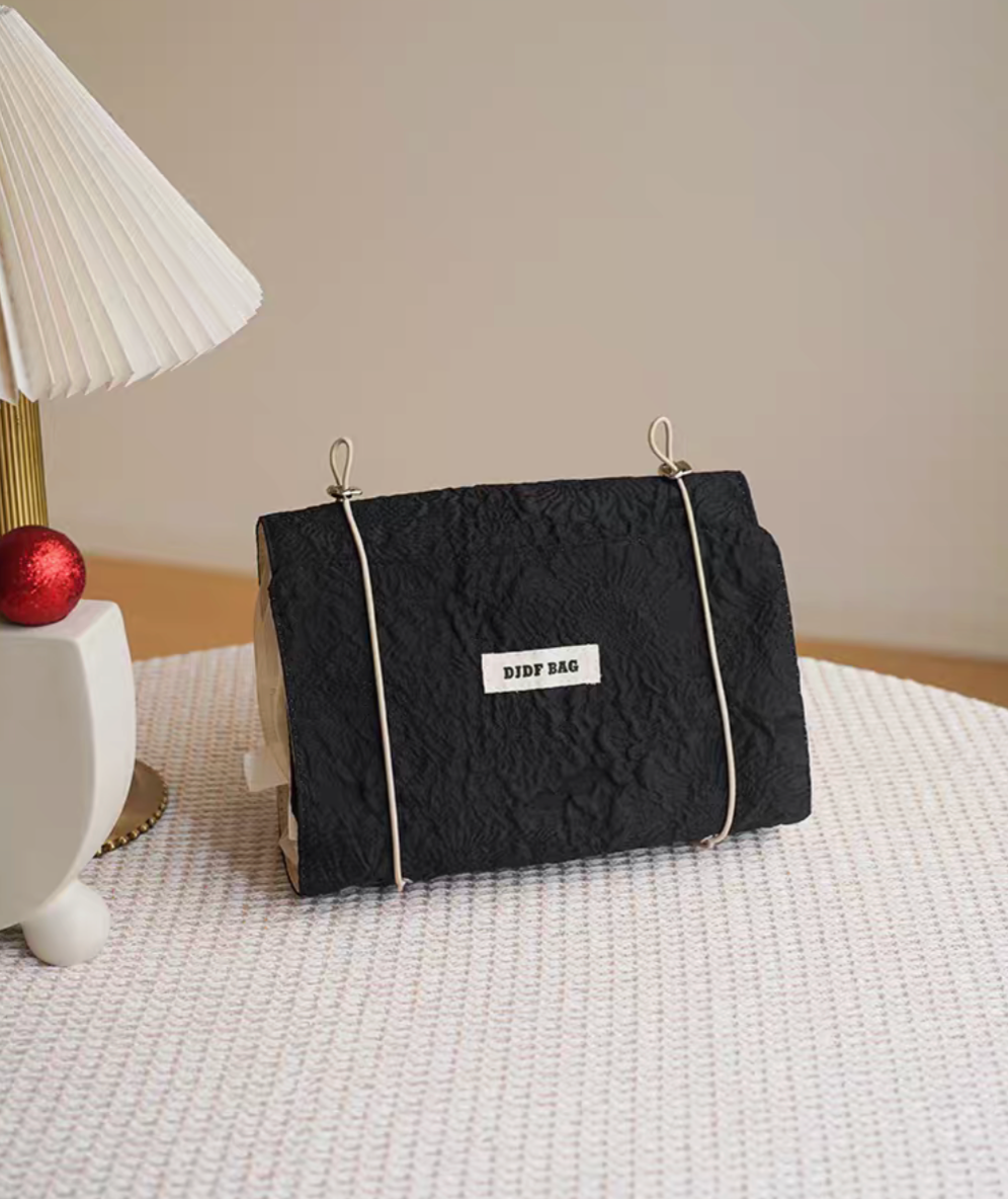 Vintage Chic Waterproof Travel Makeup Bag in black color standing upright on table beside modern lamp with clean aesthetic setup