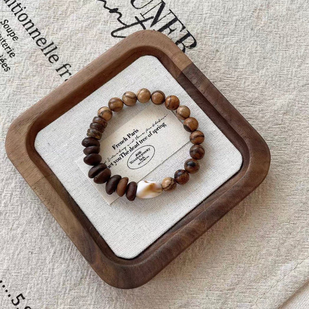 Vintage coffee bean and wood bracelet flat lay on wooden tray featuring natural wood beads coconut shell pieces and central coffee bean accent