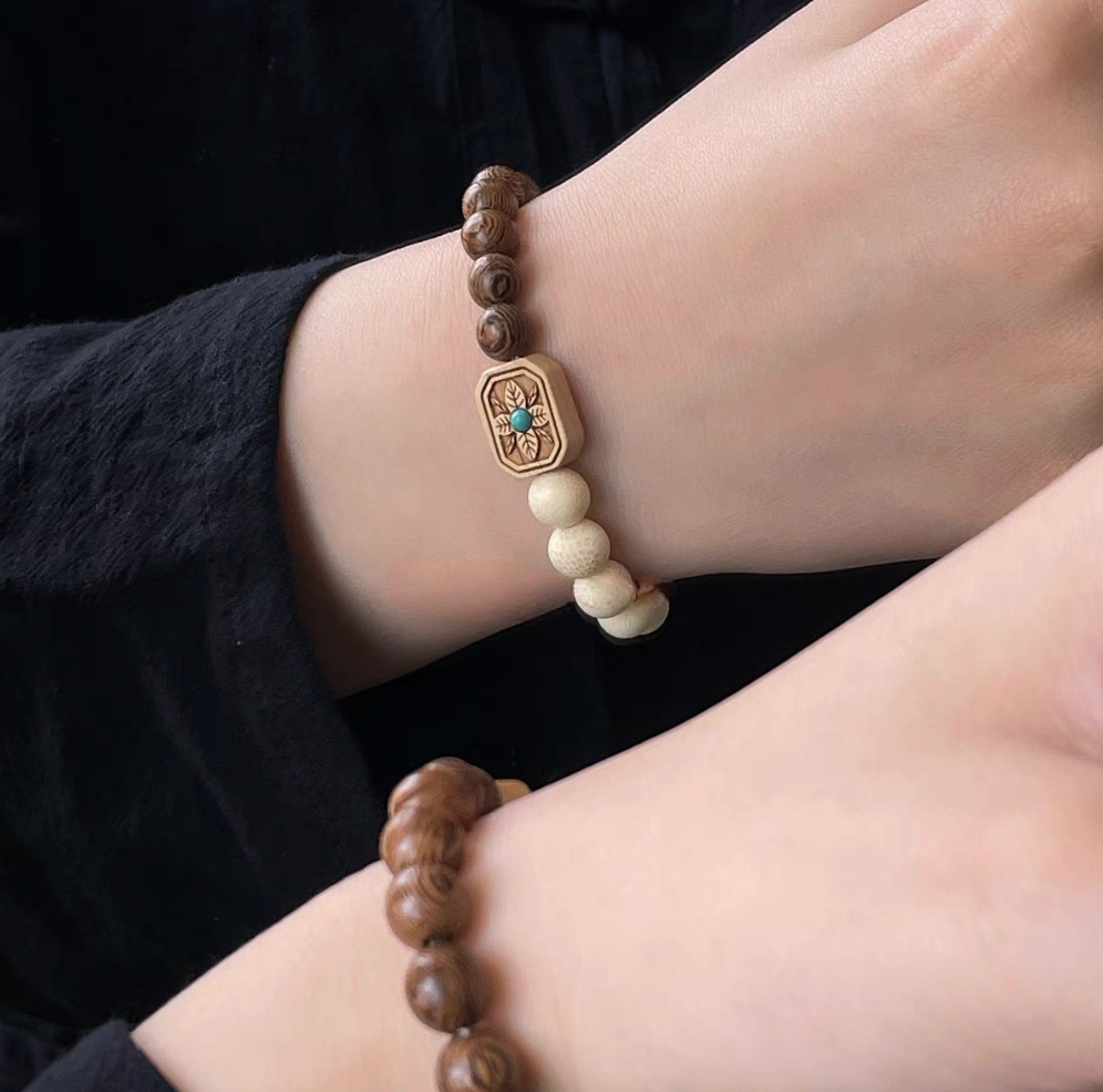 Vintage exotic wood bracelet with golden bamboo, rosewood, and boxwood beads featuring a carved center bead with turquoise detail worn on wrist