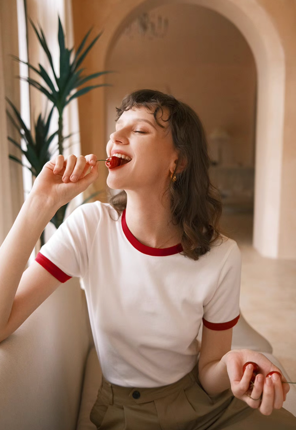 Model wearing Vintage French Contrast Collar Tee in white with red trim eating cherries showing playful vintage summer styling and fitted silhouette