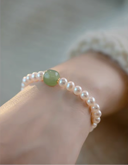 Close-up of central jade bead with pearl accents, highlighting smooth texture and natural color contrast.