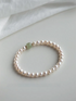 Flat lay of jade and pearl bracelet in natural color on soft neutral fabric background, highlighting minimal design.