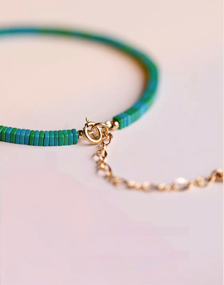 Close-up of dark green malachite bracelet highlighting gold clasp and bead alignment