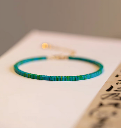 Vintage malachite bracelet in dark green tone with flat beads on a minimal background