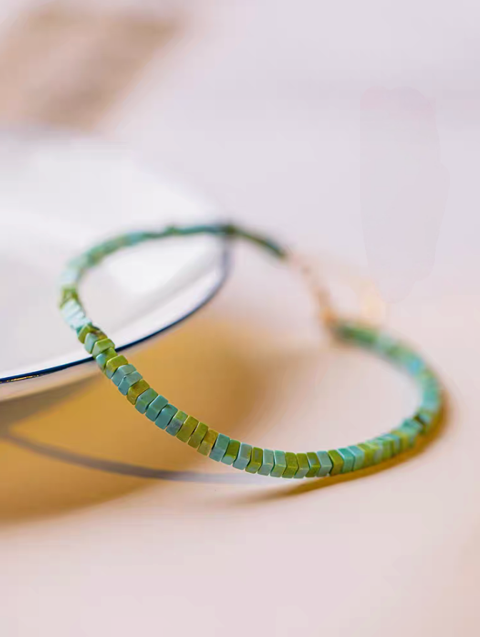 Close-up of light green vintage malachite bracelet showing curved strand and smooth square bead texture