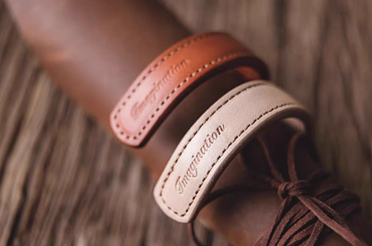 Dark brown and pink leather cuff bracelets wrapped around leather accessory showing curved shape and stitching detail