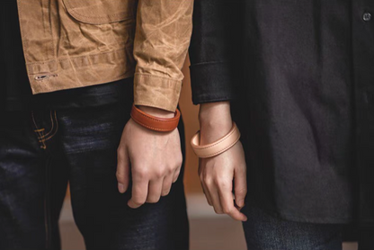 Dark brown and pink leather cuff bracelets worn on wrists paired styling front view