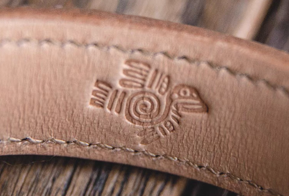 Pink leather cuff bracelet inner side close-up showing embossed thunderbird motif and natural leather texture