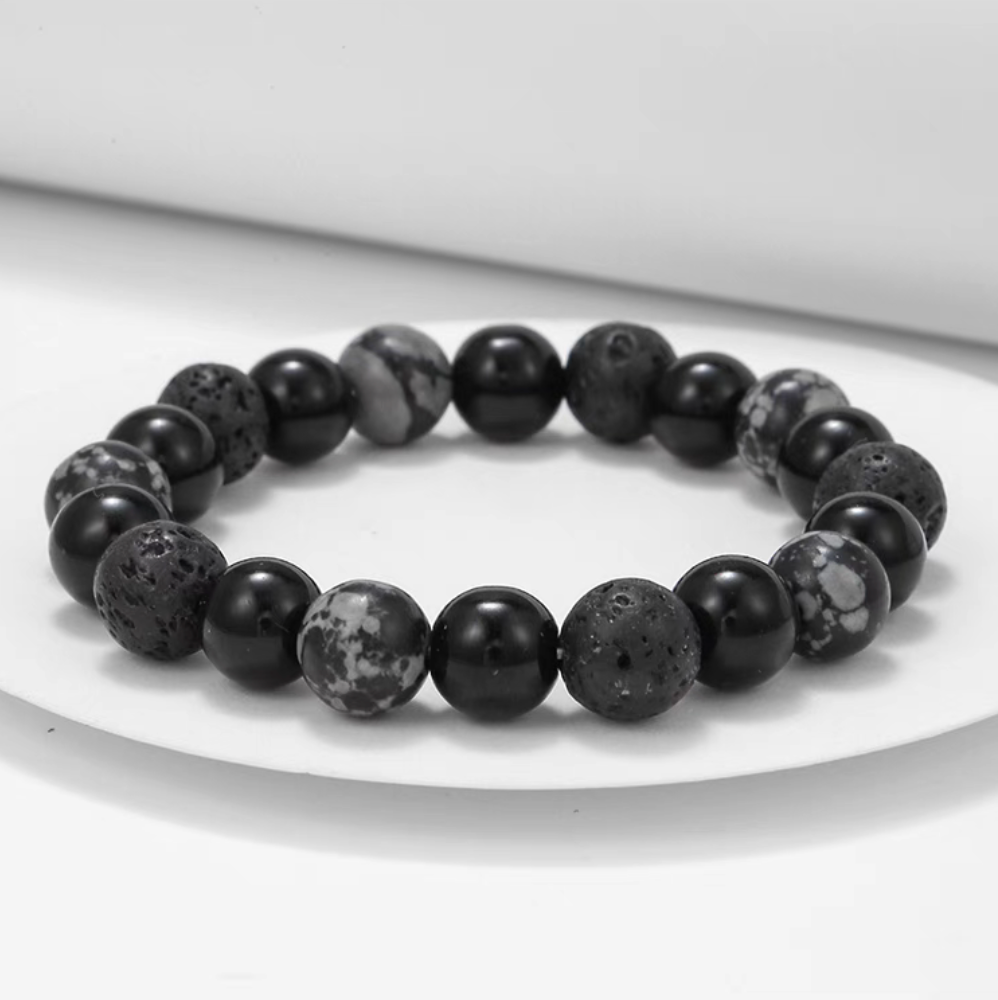 Volcanic essence black lava stone bracelet with matte lava beads, polished black beads, and gray stone accents displayed on white surface