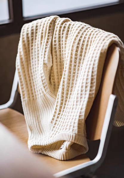 Waffle Knit Crewneck Sweater off-white draped over chair highlighting soft fabric texture and structured knit design