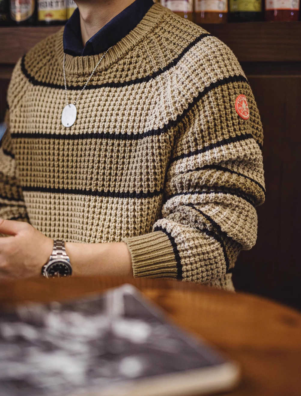 Waffle Ridge Stripe Sweater in Khaki close-up showing waffle knit texture horizontal stripe pattern and ribbed cuff detail in a casual setting