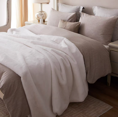 White faux fur throw blanket styled on bed creating a clean soft and luxurious bedroom feel