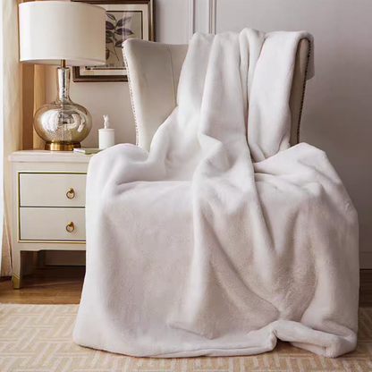 White plush faux fur throw blanket draped over chair in minimal cozy home decor setting