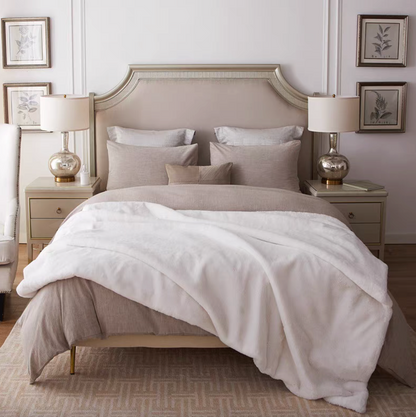 White reversible faux fur throw blanket spread across bed for cozy elegant bedroom styling