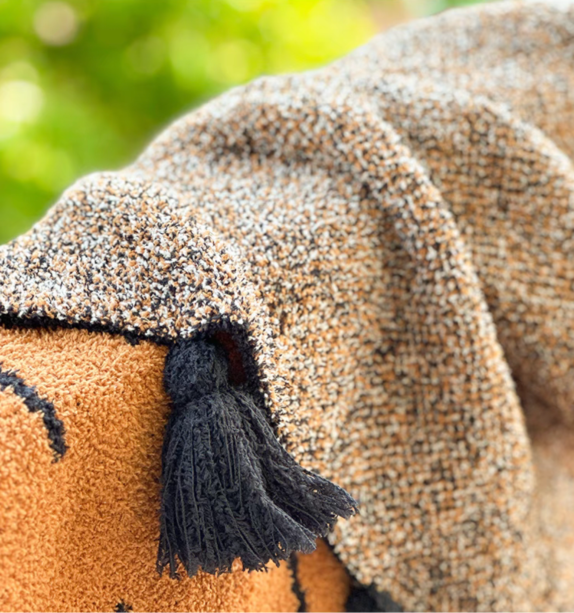 Close-up of wild cactus throw blanket corner with black tassel fringe and detailed woven fabric texture