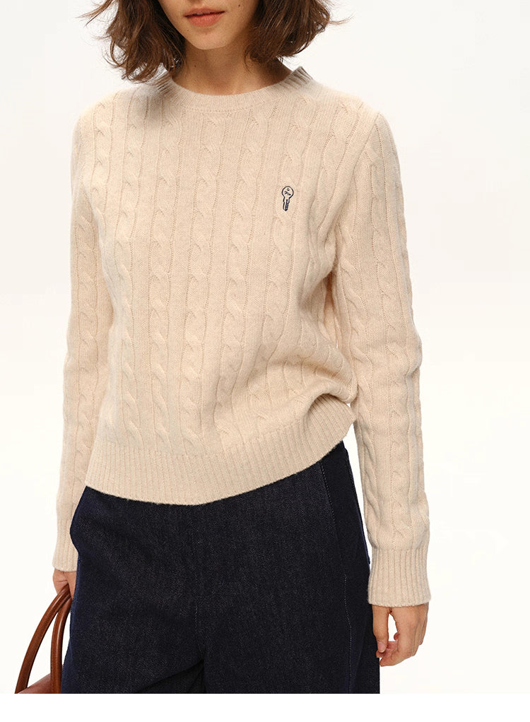 Close-up of beige almond wool sweater showing ribbed hem and chest logo