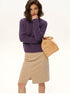 Model wearing deep purple wool cable-knit sweater with beige skirt, front view
