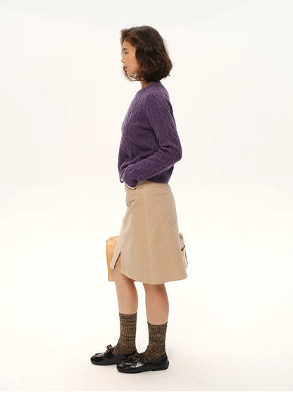 Side profile of model wearing deep purple wool cable sweater and beige skirt