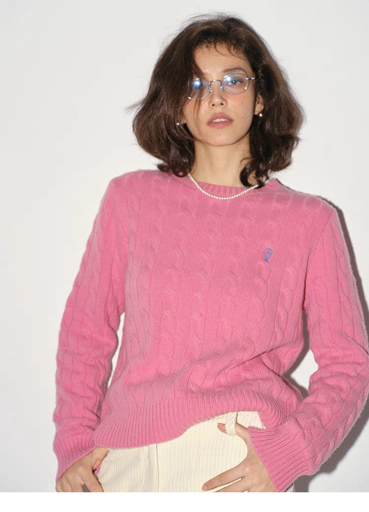 Model wearing rose pink wool cable-knit sweater in studio lighting