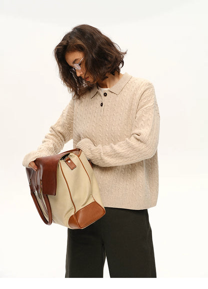 Model in beige wool cable polo sweater opening a cream canvas bag with brown leather trim