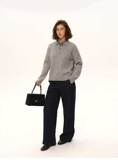 Model wearing grey cable-knit wool polo sweater styled with dark wide-leg trousers